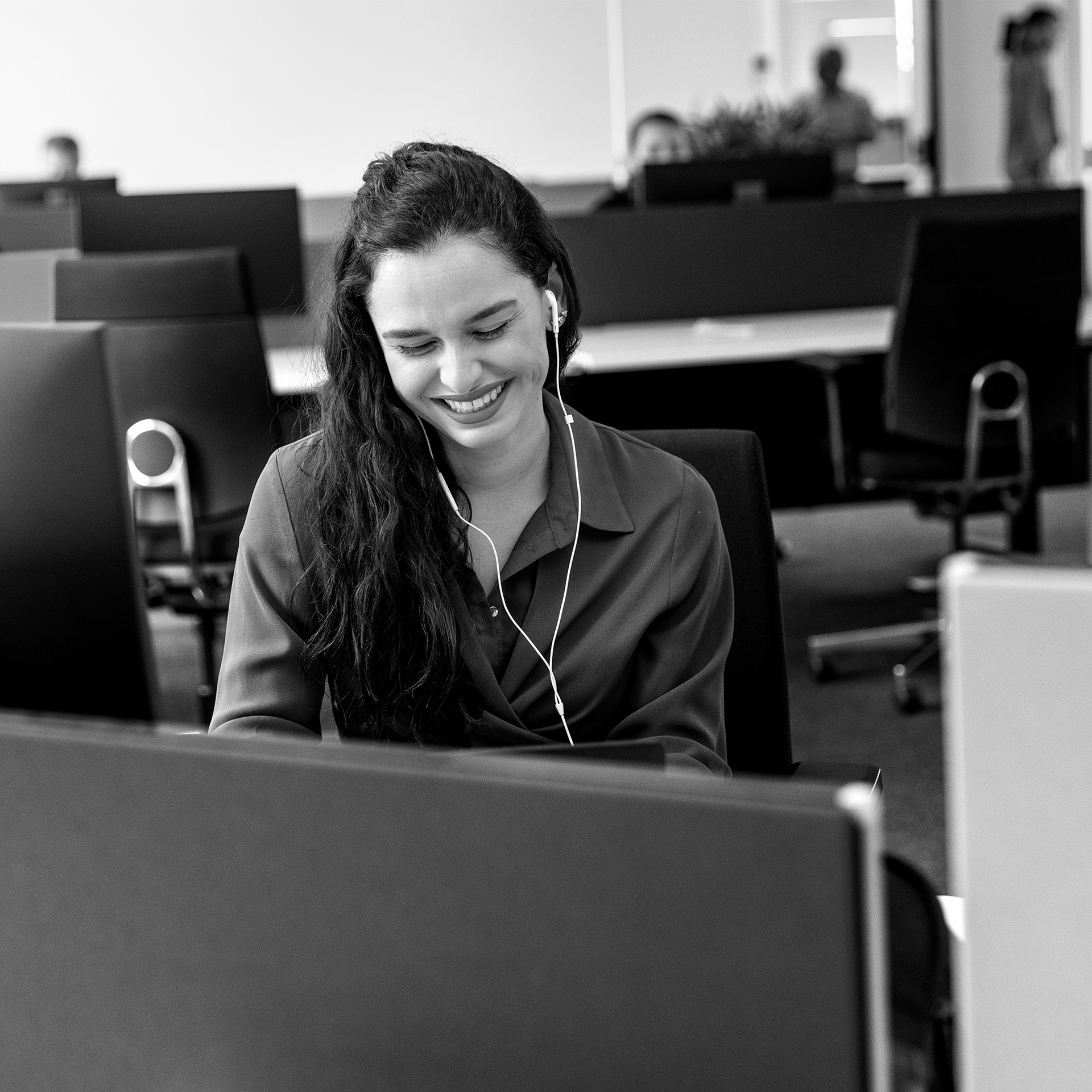 woman sitting at desk with headphones smiling